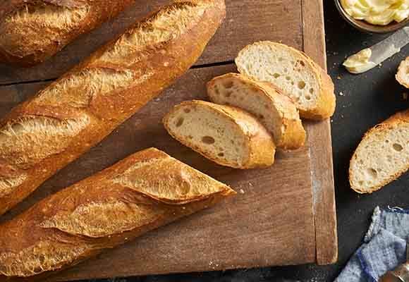 Fresh baked French baguettes sliced on a wooden board